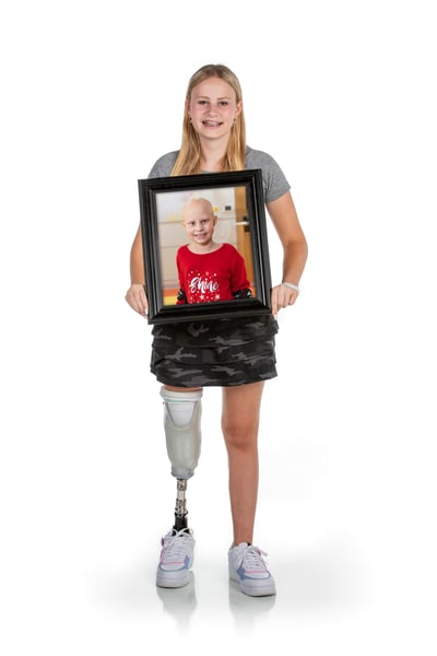 St. Jude patient smiling while holding a baby picture of themselves, reflecting on their journey at St. Jude Children's Research Hospital.