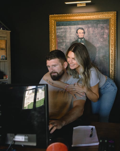 Couple hugging in a home office inside their new home, built by a new home builder, featuring a comfortable workspace, natural light, and modern design elements.